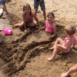 little girls create a mermaid tail in the sand