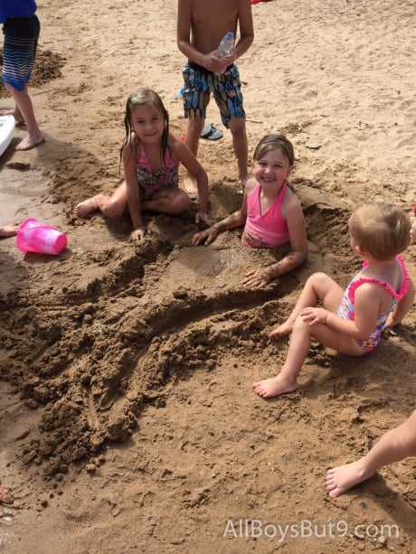 little girls create a mermaid tail in the sand