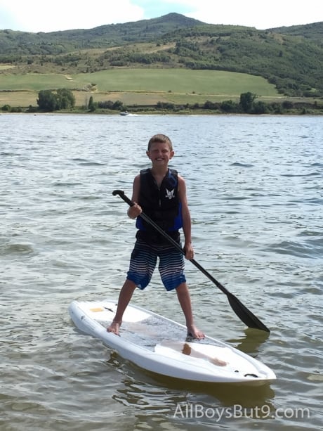 young boy on paddle board with a huge smile!