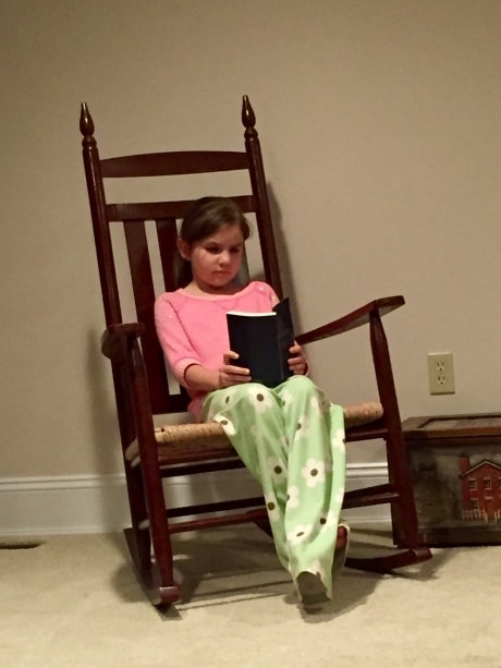 Clara reading scriptures on a big rocker.