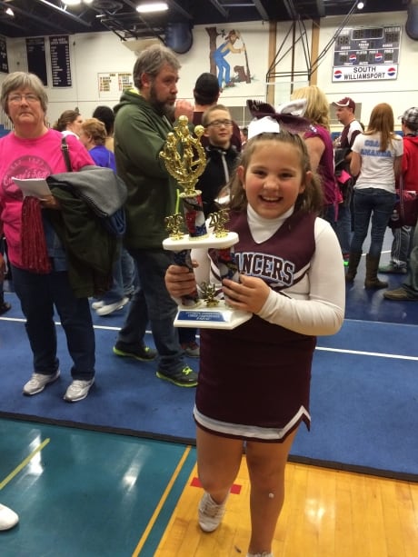 Zoie Grace holding the cheer-team trophy.